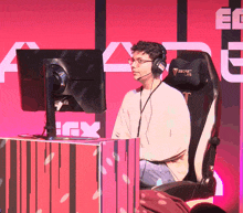 a man wearing headphones sits in front of a computer monitor and a secret lab chair