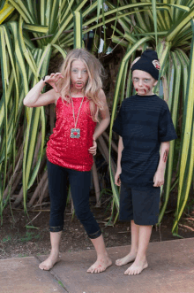 a girl in a red top and a boy in a black shirt pose for a photo