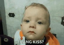 a baby is making a sad face and asking for a long kiss .