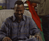 a man in a blue shirt is laughing in a chair