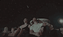 a man and a woman are sitting under a starry sky