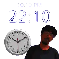 a man stands in front of a wall clock that says 10:10 pm
