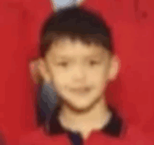 a blurry picture of a young boy in a red shirt and black shirt .