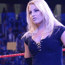 a blonde woman is standing in a wrestling ring wearing a black top