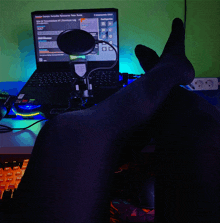 a person 's feet rest on a desk in front of a microphone and a laptop