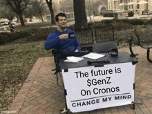 a man is sitting at a table with a sign that says `` the future is $ genz on cronos change my mind ''