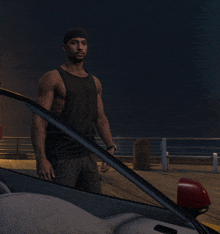 a man in a black tank top is standing next to a car on a pier