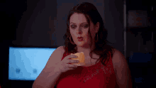 a woman in a red dress is holding a candle in her hand .