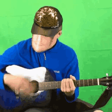 a man wearing a blue jacket and a hat is playing an acoustic guitar .