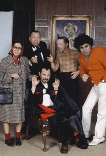 a group of people are posing for a picture in front of a painting