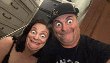 a man and a woman are making funny faces and the man is wearing a hat that says gs