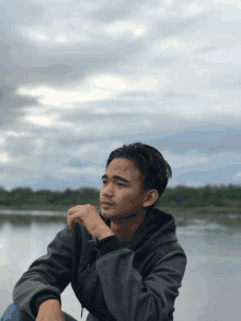 a young man in a gray jacket sits on a beach