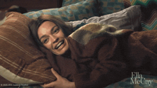 a woman laying on a bed with ella mccay on the bottom