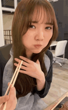 a woman with chopsticks in her hand making a funny face