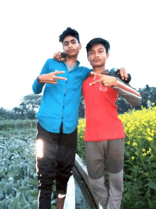 two young men posing for a picture with one wearing a red shirt