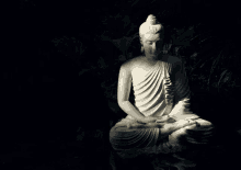 a white statue of a buddha sitting in a dark room