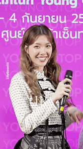a woman holds a microphone in front of a purple background with the number 4 on it