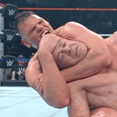 two men are wrestling in a wrestling ring and one of them is holding the other 's neck .