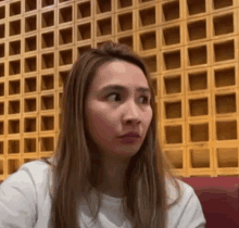 a woman with long hair is sitting in front of a wooden wall .