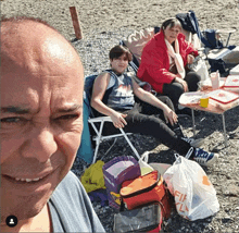 a man is taking a picture of himself and his family on the beach with a bag that says fifa on it