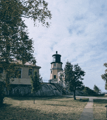 a lighthouse sits on top of a grassy hill