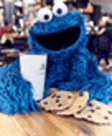 a cookie monster is sitting on top of a pile of cookies on a table .