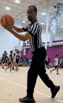 a referee is holding a wilson basketball in his hands