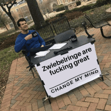 a man is sitting at a table with a sign that says change my mind