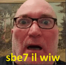 a bald man with glasses and a beard says sbe7 il wiw in yellow letters