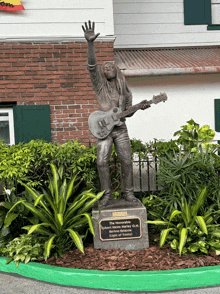 a statue of a man holding a guitar in front of a brick building