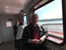 a man in a red shirt stands in front of a window