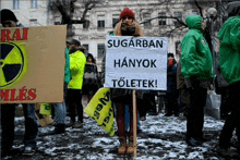 a woman is holding a sign that says sugarban hangok toletek