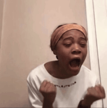 a young woman wearing a headband is making a funny face with her mouth open .