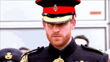 a man with a beard is wearing a red hat with a gold emblem on it