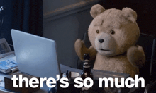 a teddy bear is sitting at a desk in front of a laptop and a bottle of beer .