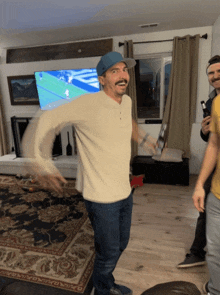 a man in a blue hat is dancing in front of a tv screen