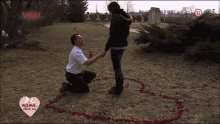 a man is kneeling down to propose to a woman with a heart made of rose petals in the background