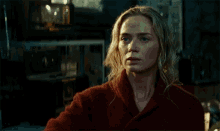 a woman in a red robe is standing in a dark room looking at the camera .