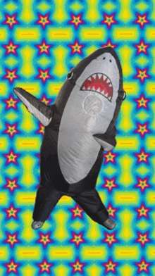 a person in an inflatable shark costume dancing on a colorful background