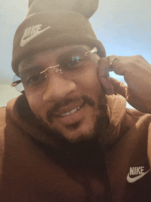 a man wearing a nike beanie and a brown nike hoodie