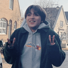 a young man wearing a grey hoodie that says carama on it