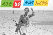 a black and white photo of a man holding a gun in the middle of a desert