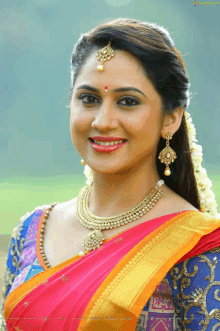 a woman wearing a necklace and earrings smiles for a photo