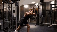 a man in a black tank top is using a machine in a gym with a sign that says ' a ' on it