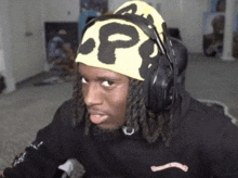 a man with dreadlocks wearing headphones and a headband with the letter p on it