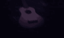 a pink guitar is sitting in the dark with a black background