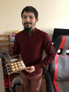 a man in a maroon shirt holds a box of chocolates