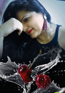 a woman in a black tank top with red earrings is surrounded by water and cherries