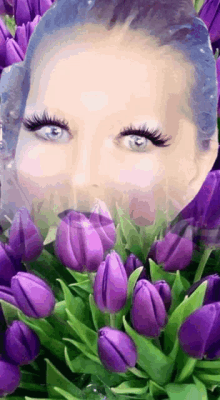 a woman 's face is surrounded by purple flowers and leaves