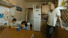 a man stands in a kitchen with two children and a clock on the wall that says ' clock '